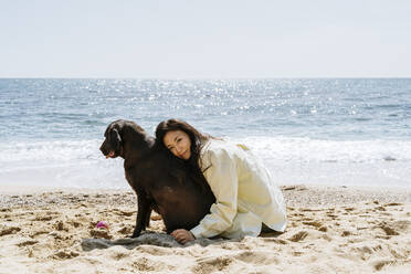 Frau umarmt Labrador-Hund im Sand am Strand - AFVF08685