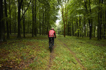 Sportsman riding bicycle in forest - PMF01781