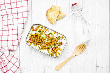 Studio shot of bottle of water, napkin, wooden cutlery, flatbread and lunch box of yogurt with chick-peas, cucumbers and radishes - LVF09147