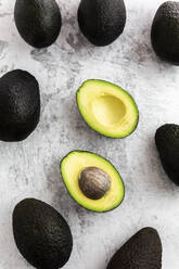 Studioaufnahme einer halbierten Avocado, umgeben von ganzen Avocados - GIOF12514