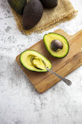 Studio shot of halved avocado lying on cutting board - GIOF12522