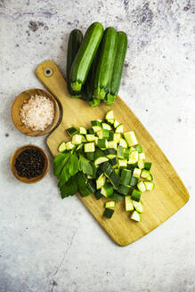 Studio shot of chopped parsley and zucchinis and wooden bowls with black peppercorns and Himalayan salt - GIOF12538