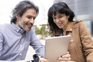 Älteres Unternehmerpaar arbeitet auf der Terrasse an einem digitalen Tablet - JCCMF01996