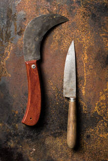 Draufsicht auf scharfe Messer mit schäbigen Klingen, die auf einem rostigen Metalltisch liegen - ADSF23250