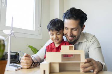 Männlicher Architekt und Sohn lächelnd bei der Betrachtung eines Hausmodells - JCCMF02019