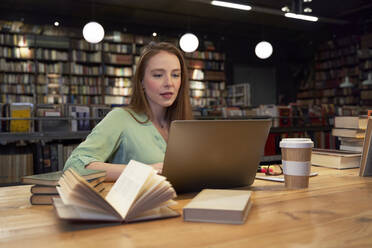 Beautiful woman using laptop while studying in library - VEGF04361