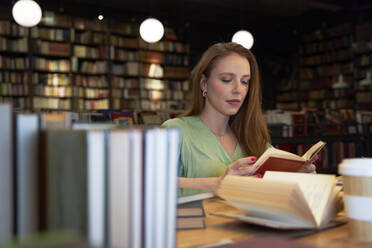 Junge Frau liest ein Buch in der Bibliothek - VEGF04373