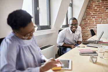 Smiling male professional looking at female colleague in office - ZEDF04165