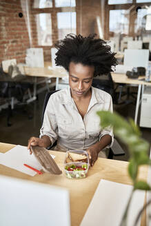 Afro-Geschäftsfrau beim Öffnen eines Containers in der Mittagspause im Büro - ZEDF04168