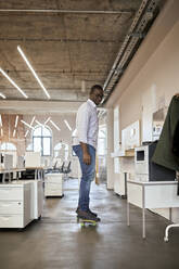 Male entrepreneur riding skateboard in office - ZEDF04171