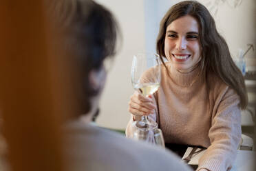Lächelnde Frau mit Weinglas sieht ihren Freund im Restaurant an - EGAF02339
