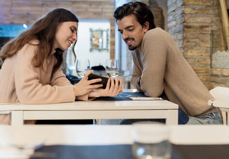 Pärchen schaut im Restaurant auf sein Smartphone - EGAF02342