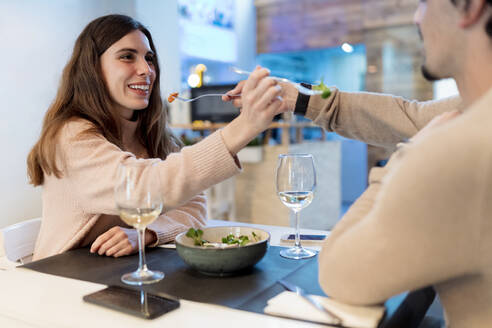 Ehepaar füttert sich gegenseitig mit Salat am Restauranttisch - EGAF02348