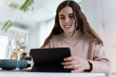 Lächelnde schöne Frau mit digitalem Tablet am Restauranttisch - EGAF02354