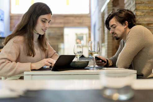 Junges Paar nutzt drahtlose Technologie am Restauranttisch - EGAF02355