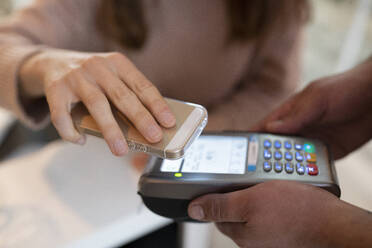 Frau bezahlt im Restaurant mit ihrem Smartphone - EGAF02358