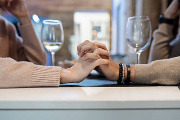 Ehepaar mit verschränkten Händen im Restaurant sitzend - EGAF02359