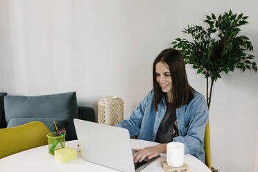 Lächelnde Geschäftsfrau, die im Büro zu Hause am Laptop arbeitet - XLGF01626