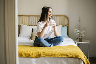 Lächelnde Frau mit Kaffee auf dem Bett zu Hause - XLGF01665