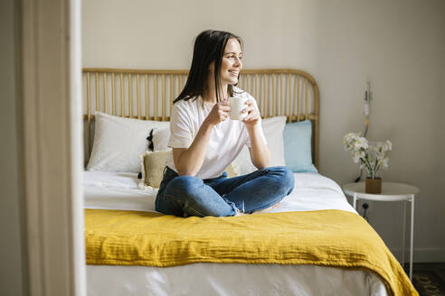 Lächelnde Frau mit Kaffee auf dem Bett zu Hause - XLGF01665