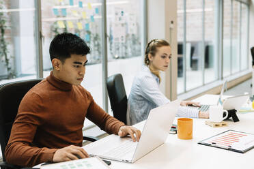 Männlicher Unternehmer, der mit einem Kollegen im Büro am Laptop arbeitet - XLGF01673