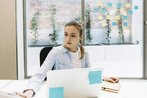 Weibliche Fachkraft mit Laptop bei der Arbeit im Büro - XLGF01676