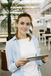 Smiling businesswoman holding digital tablet at office - XLGF01715