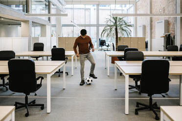 Junger Unternehmer spielt mit Fußball im Büro - XLGF01720