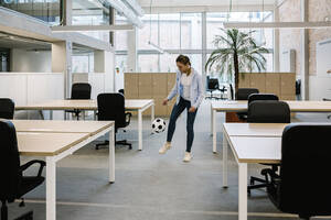 Geschäftsfrau spielt mit Fußball im Coworking-Büro - XLGF01722