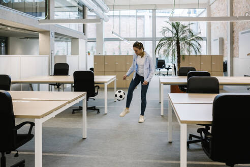 Geschäftsfrau spielt mit Fußball im Coworking-Büro - XLGF01722