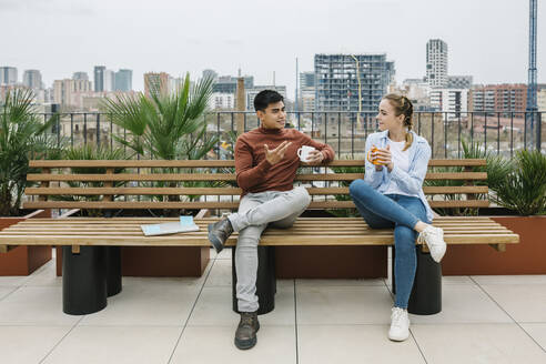 Male and female entrepreneurs discussing while having coffee at rooftop - XLGF01724