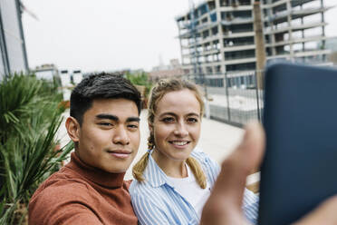 Male and female entrepreneurs taking selfie through mobile phone at terrace - XLGF01731