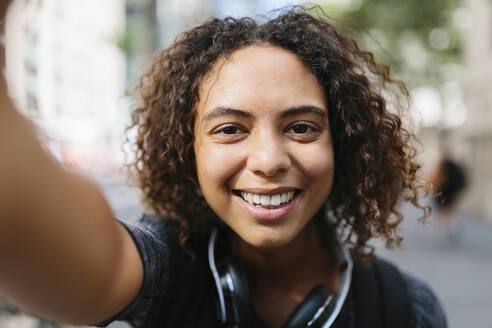 Frau mit lockigem Haar macht Selfie in der Stadt - BOYF01987