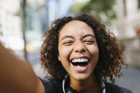 Lachende junge Frau nimmt Selfie in der Stadt - BOYF01988