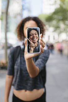 Frau zeigt Selfie auf Smartphone in der Stadt - BOYF01990