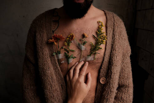 Woman's hands placing flowers on man's chset - ADSF23371