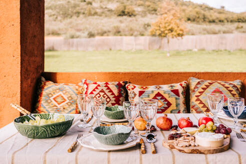 Tisch mit Geschirr und verschiedenen reifen Früchten und köstlichen Vorspeisen auf der Terrasse serviert - ADSF23434