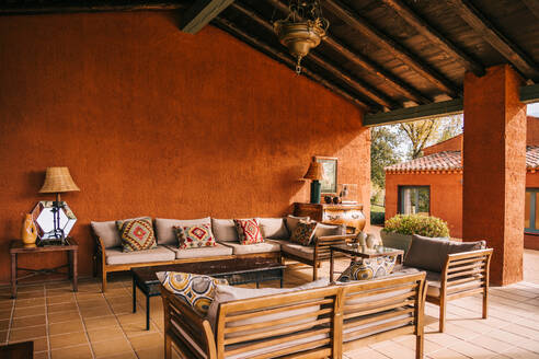 Bequeme Sofas und Tisch auf der Terrasse unter dem Holzdach der Hütte im Sommer platziert - ADSF23436