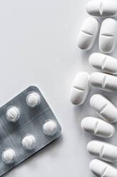 Nahaufnahme von oben Stapel von Pillen und Blister mit weißen Tabletten auf weißem Hintergrund platziert - ADSF23448