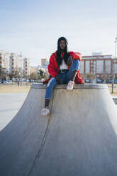 Young woman sitting at skateboard park - MPPF01682