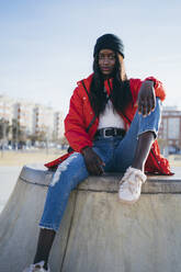 Young woman sitting on ramp at skateboard park - MPPF01683