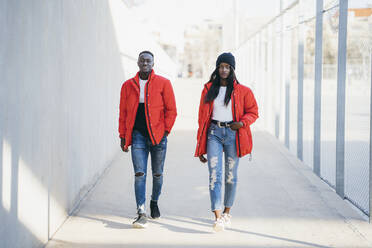 Boyfriend and girlfriend walking on footpath during sunny day - MPPF01697