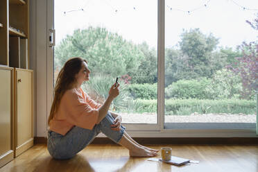 Smiling woman using smart phone while sitting at home - AFVF08698
