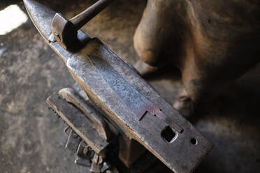 Männlicher Metallarbeiter, der in einer Werkstatt am Amboss steht - AODF00481