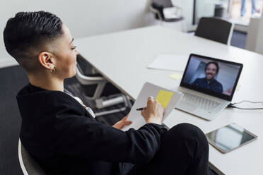 Unternehmerin bei der Planung einer Geschäftsstrategie per Videoanruf am Laptop im Büro - MEUF02541