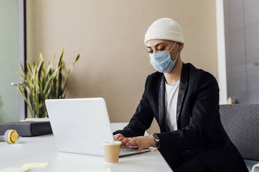 Junger Berufstätiger bei der Arbeit am Laptop im Büro während der COVID-19 - MEUF02636