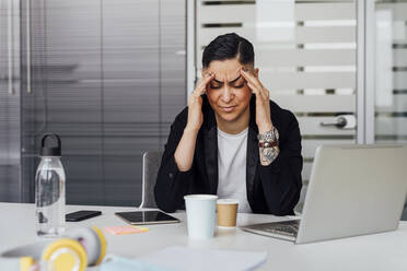 Businesswoman with head in hands at office - MEUF02641