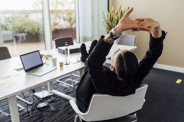 Young professional resting on chair in office - MEUF02645