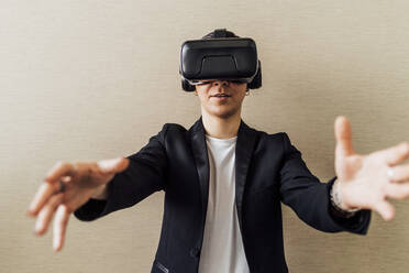 Geschäftsfrau gestikuliert bei der Verwendung eines Virtual-Reality-Headsets im Büro - MEUF02649