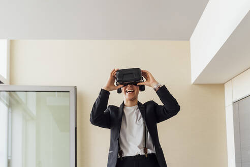 Glückliche Geschäftsfrau mit Virtual-Reality-Headset im Büro - MEUF02658